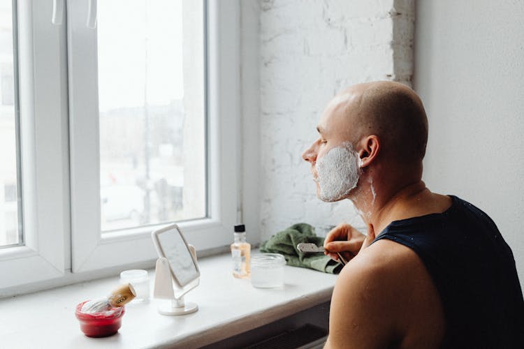 Man Shaving In Front Of A Mirror