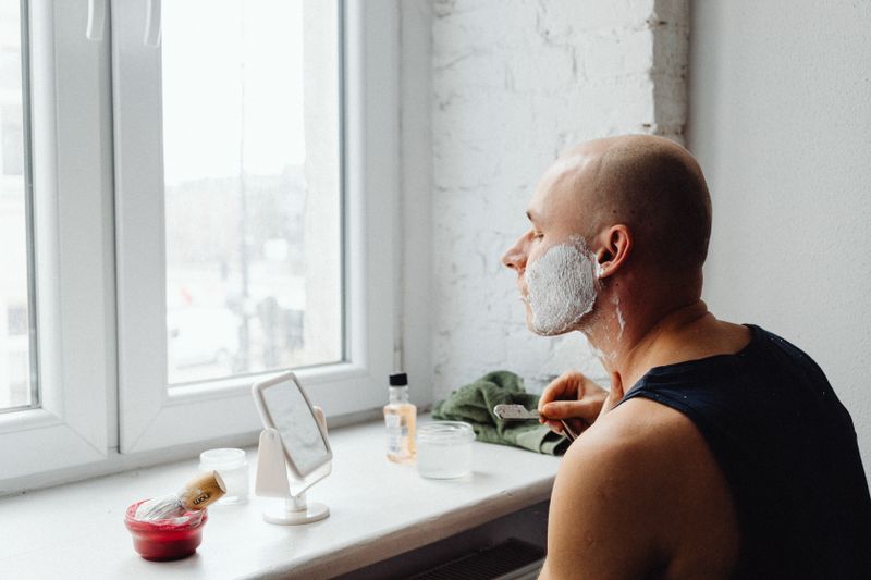 Homme se rasant avec un rasoir de surete devant un miroir dans une salle de bain minimaliste