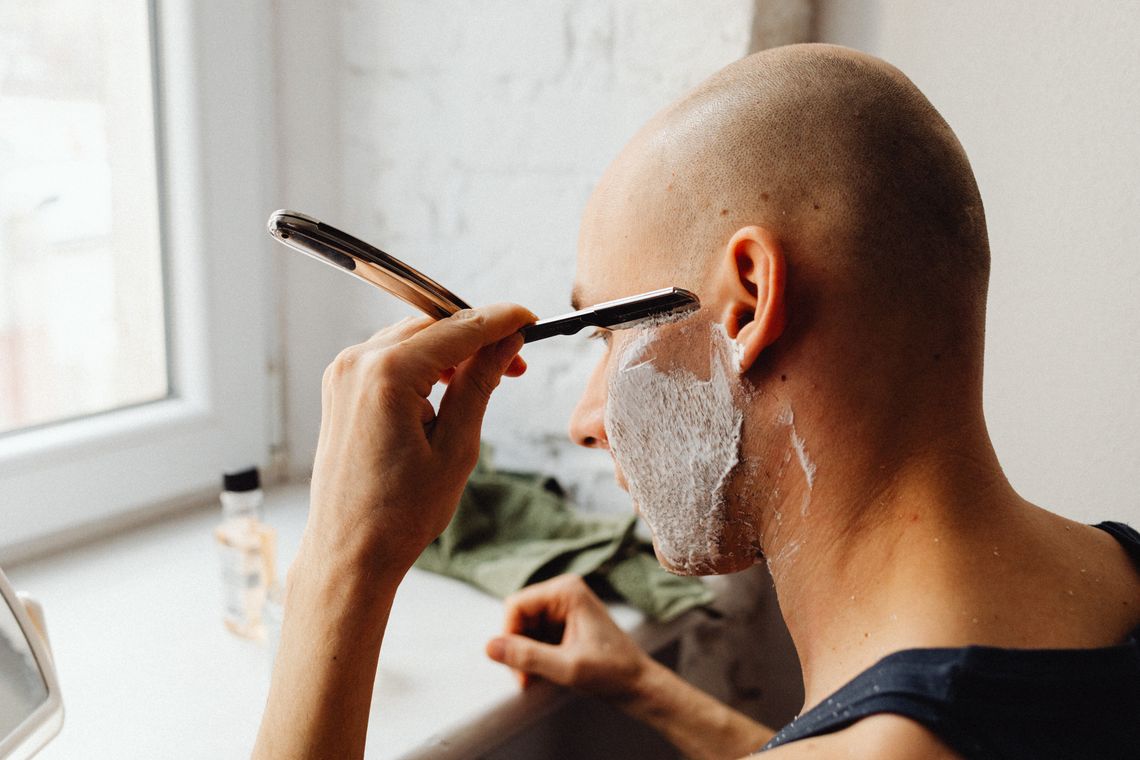 Man completing a careful shaving routine in a bathroom