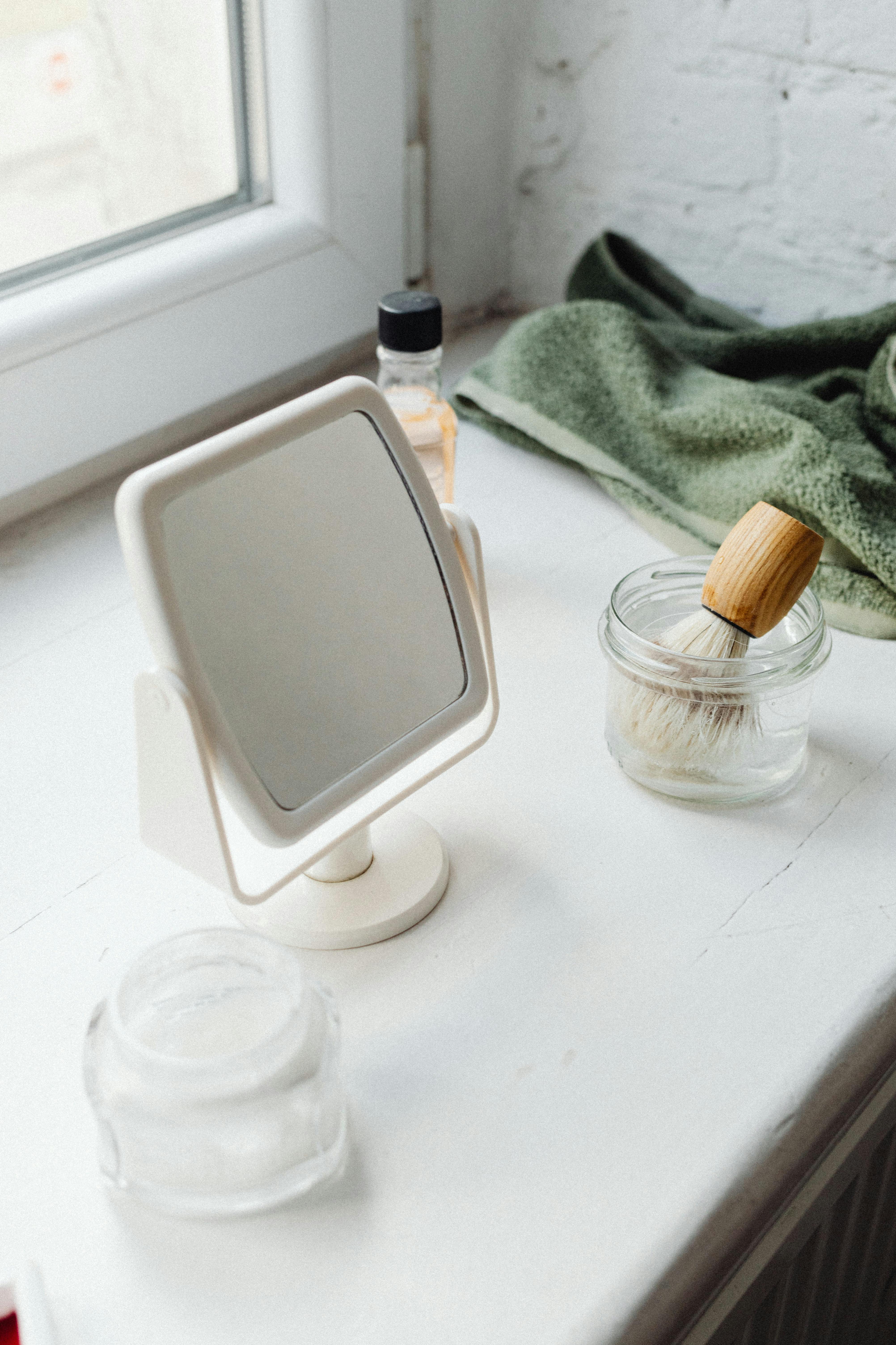 a mirror beside glass containers and shaving brush