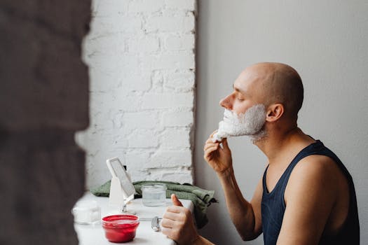 Side view of a bald man using shaving cream at home. Indoor bathroom setting.