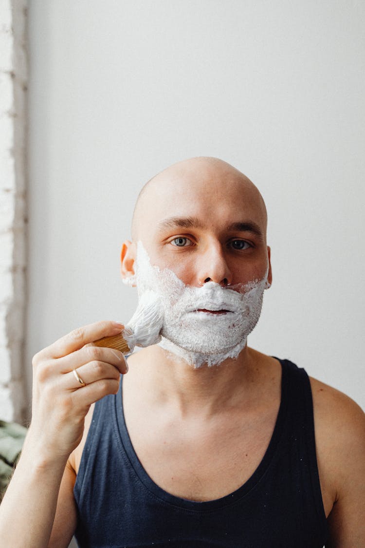 Man In Blue Tank Top Applying Cream On Face With Shaving Brush