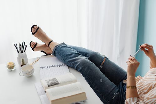 Free A casual and relaxed workspace with a woman in denim jeans, feet on desk, enjoying a break. Stock Photo