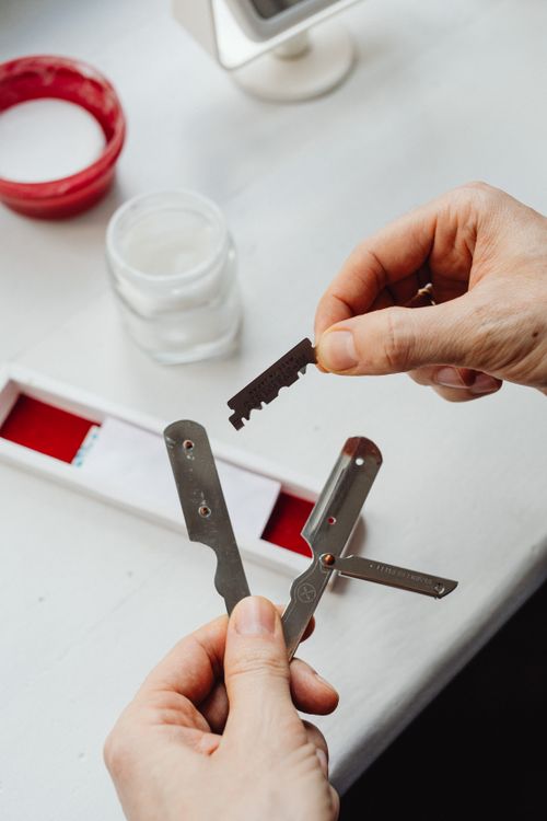 Free Close-up of hands carefully assembling a razor blade with open tools on a table. Stock Photo