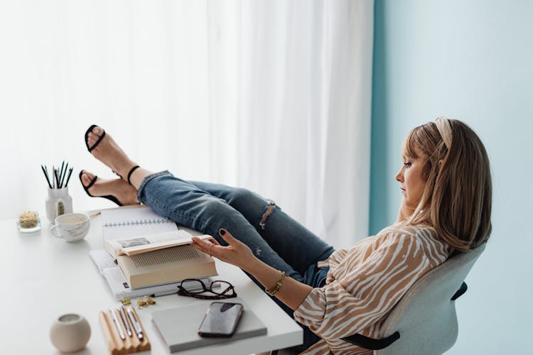 Woman Sitting In An Office Chair With Feet On Table