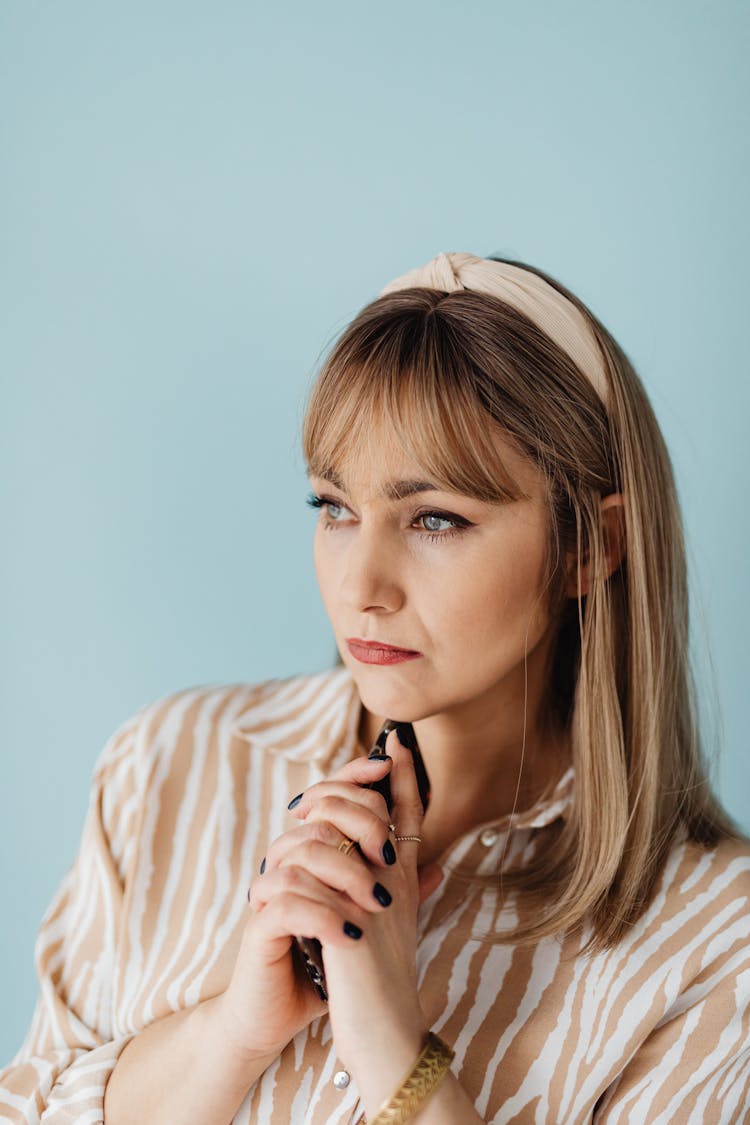 A Woman Holding Her Smartphone Under Her Chin