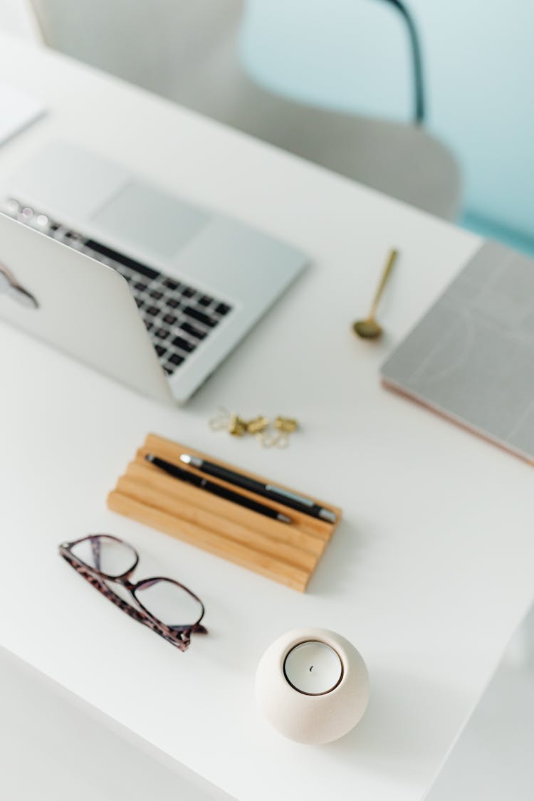 Eyeglasses, Laptop, Pens And A Candle On A Desk 