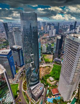 Breathtaking aerial view of Jakarta's skyline with towering skyscrapers under a dramatic sky.