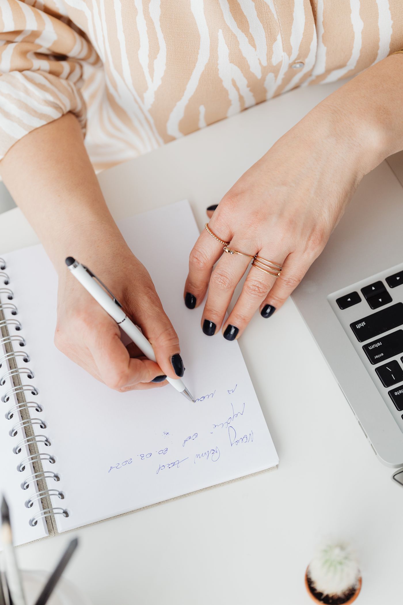 Des mains prennent des notes dans un carnet à côté d'un ordinateur portable