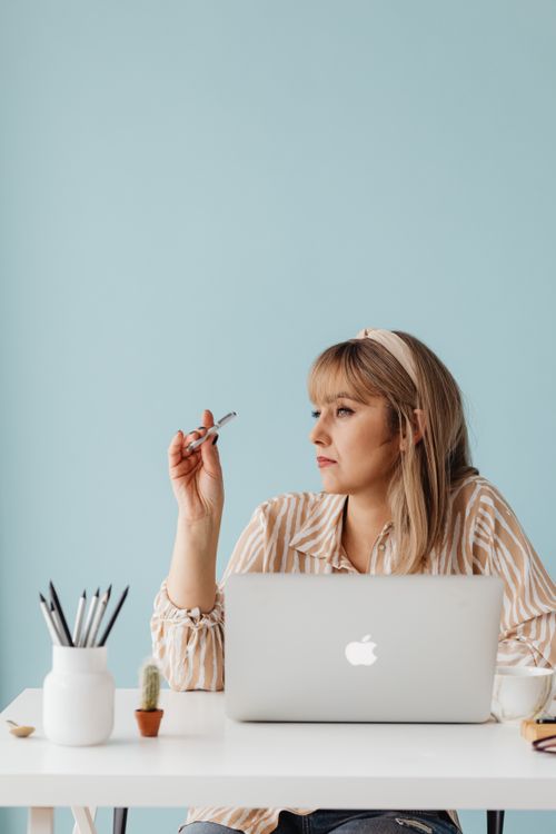 Free Thoughtful woman working at desk with laptop, contemplating ideas. Stock Photo