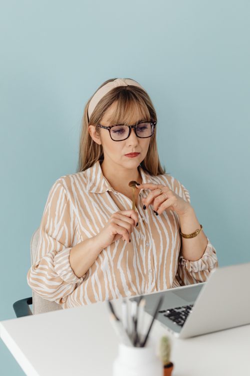 Free Focused woman with blonde hair and glasses working on a laptop at a desk indoors. Stock Photo