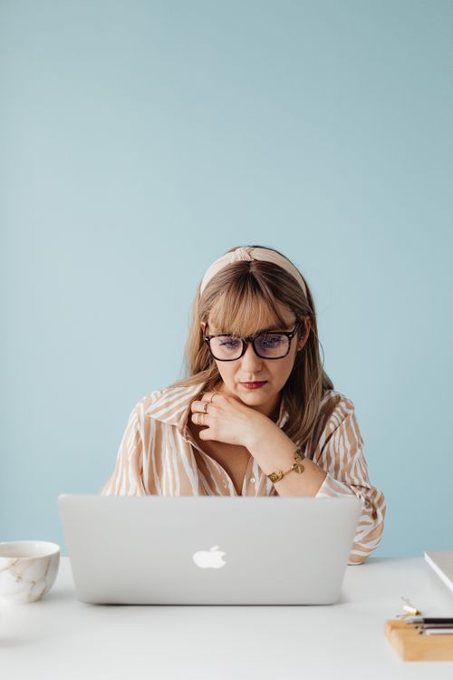 Free A woman working on her laptop with a coffee cup, set indoors in a modern minimalist style. Stock Photo