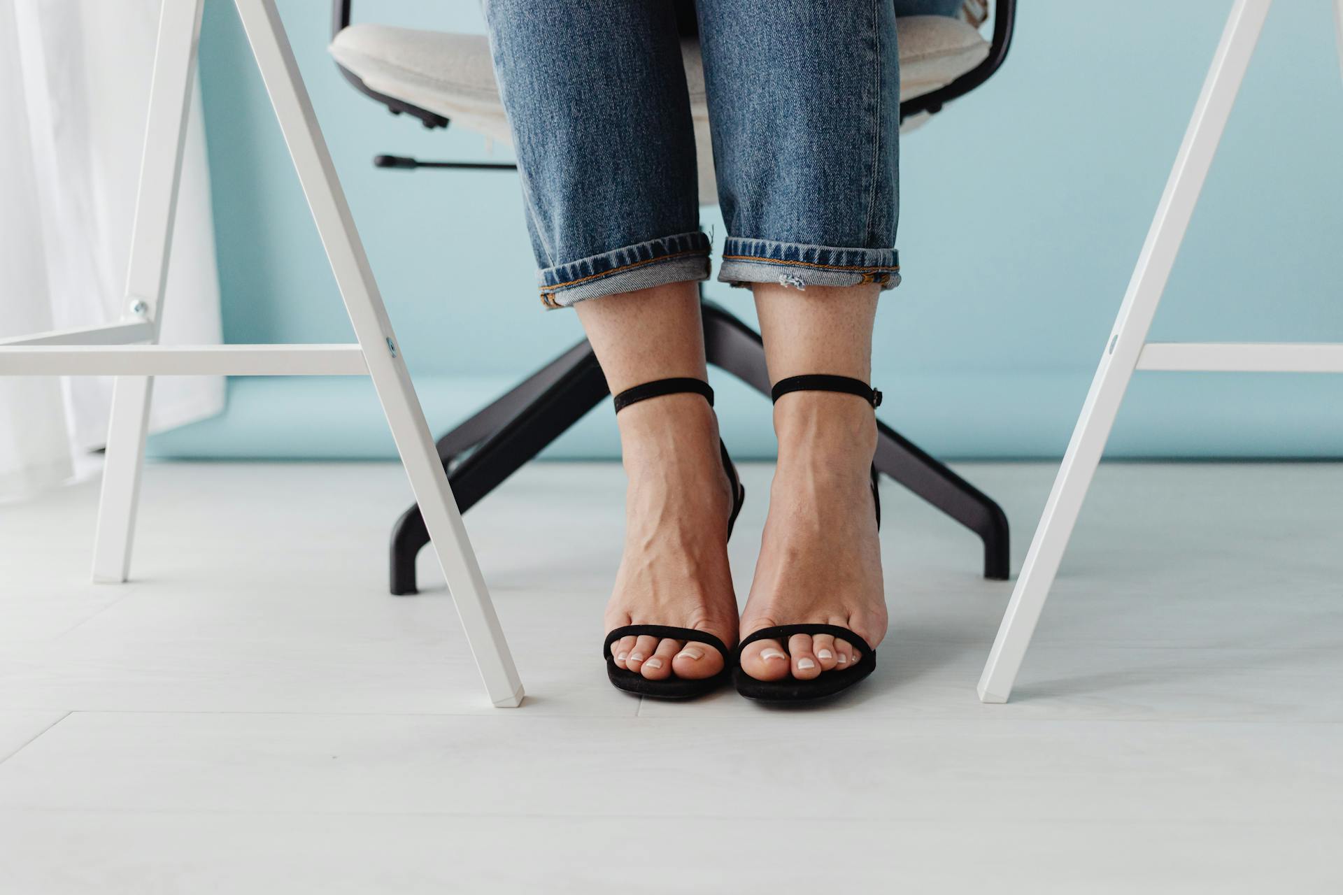 Shot of Female Legs Wearing Black High Heel Shoes against Pastel Blue Background