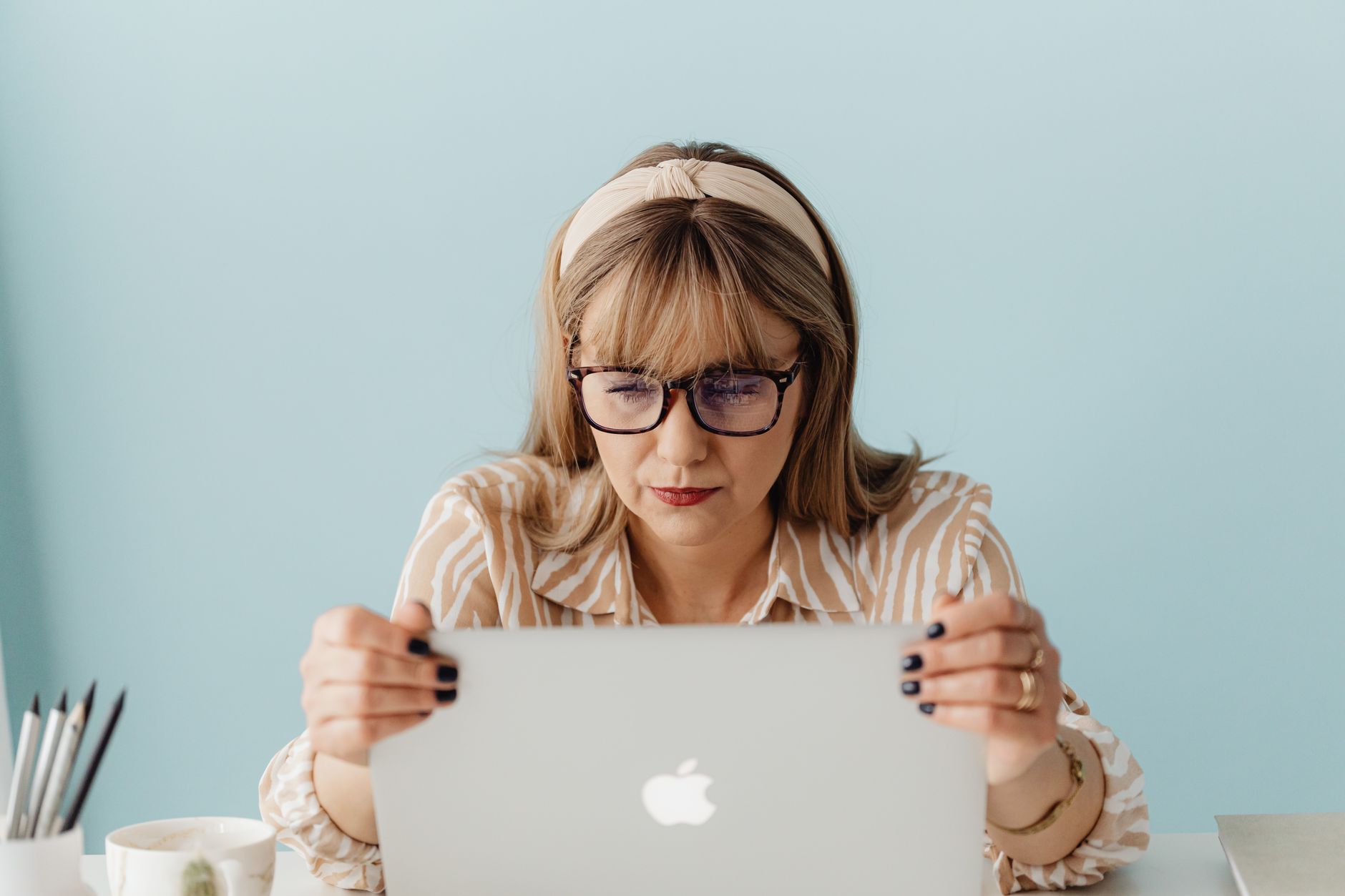 Focused woman with glasses intently using a laptop in an office setting.