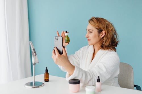 A Woman Taking Selfie while Holding a Bottle