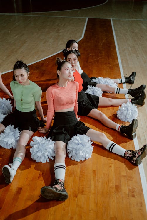 Cheering Squad Sitting on the Floor while Looking Afar