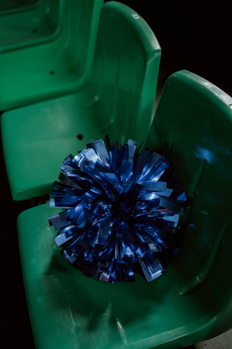 
A Blue Pompom  On A Green Plastic Chair