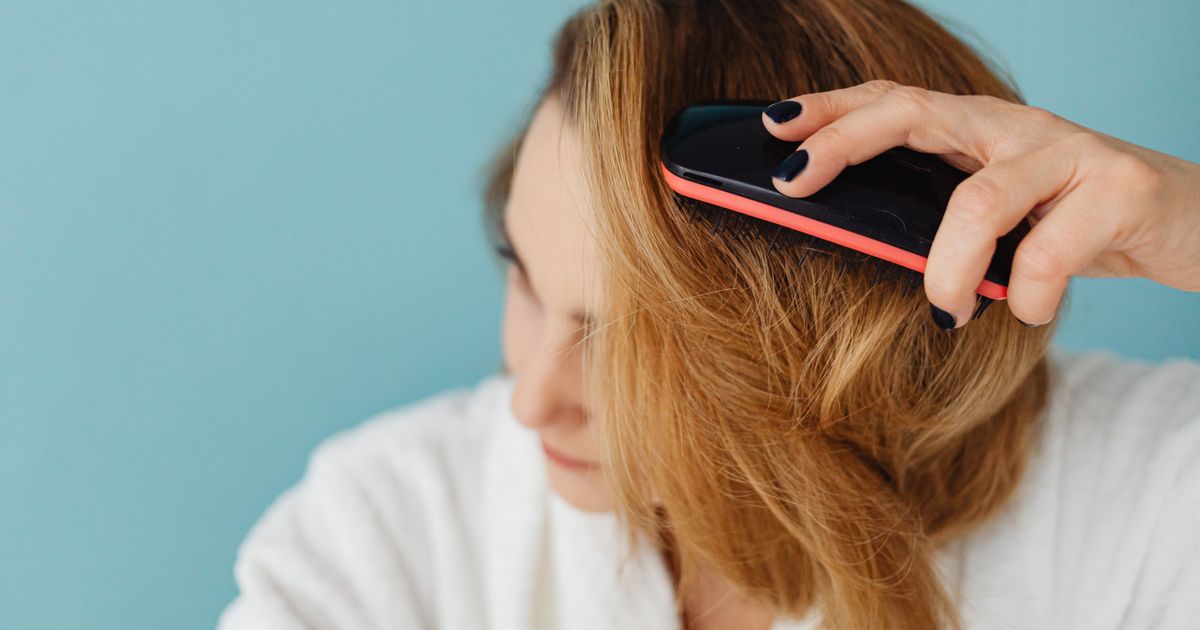A woman brushing her hair with a detangling brush