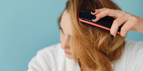 A woman brushing her hair with a detangling brush