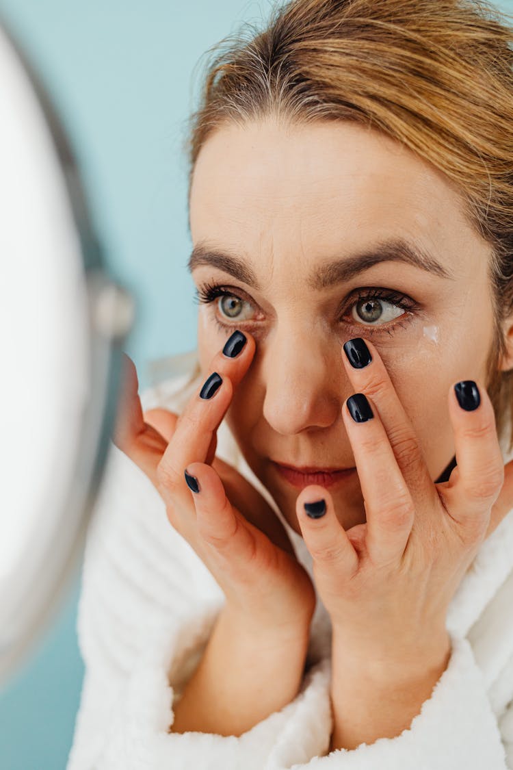 Woman With Black Manicure Applying Skincare Under Eyes