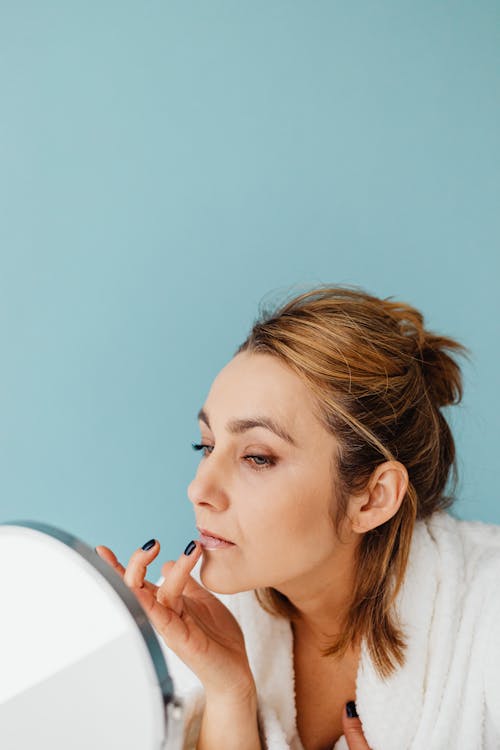 Free A Woman Applying a Cream on Her Lips Stock Photo