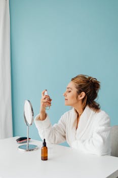 Adult woman in bathrobe applying setting spray at vanity. Modern and calming beauty routine.