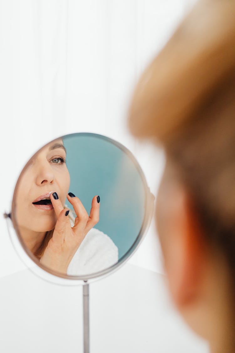 Woman Applying Lip Balm In Mirror