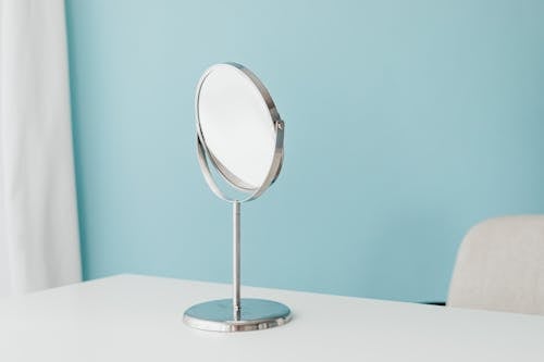 Round Mirror on a White Desk and Pastel Blue Wall