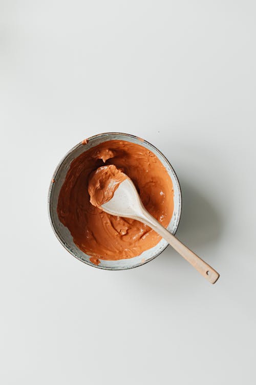 Top View of an Orange Clay Cosmetic Mask with a Spoon 