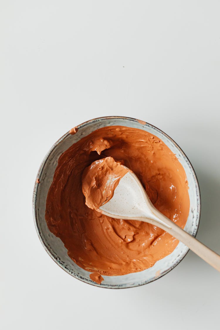 Top View Of An Orange Clay Cosmetic Mask With A Spoon 