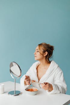 Woman in a white bathrobe mixing a face mask in a serene self-care routine.