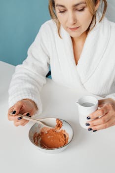 Woman in bathrobe mixing ingredients for a homemade face mask.