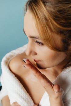 Close-up of a woman applying skincare cream to her shoulder, highlighting self-care and beauty routine.