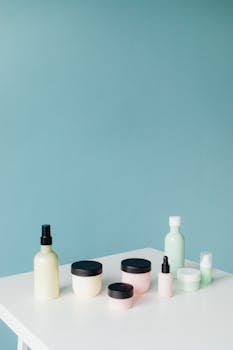Aesthetic arrangement of skincare bottles and jars on a table with a blue background.