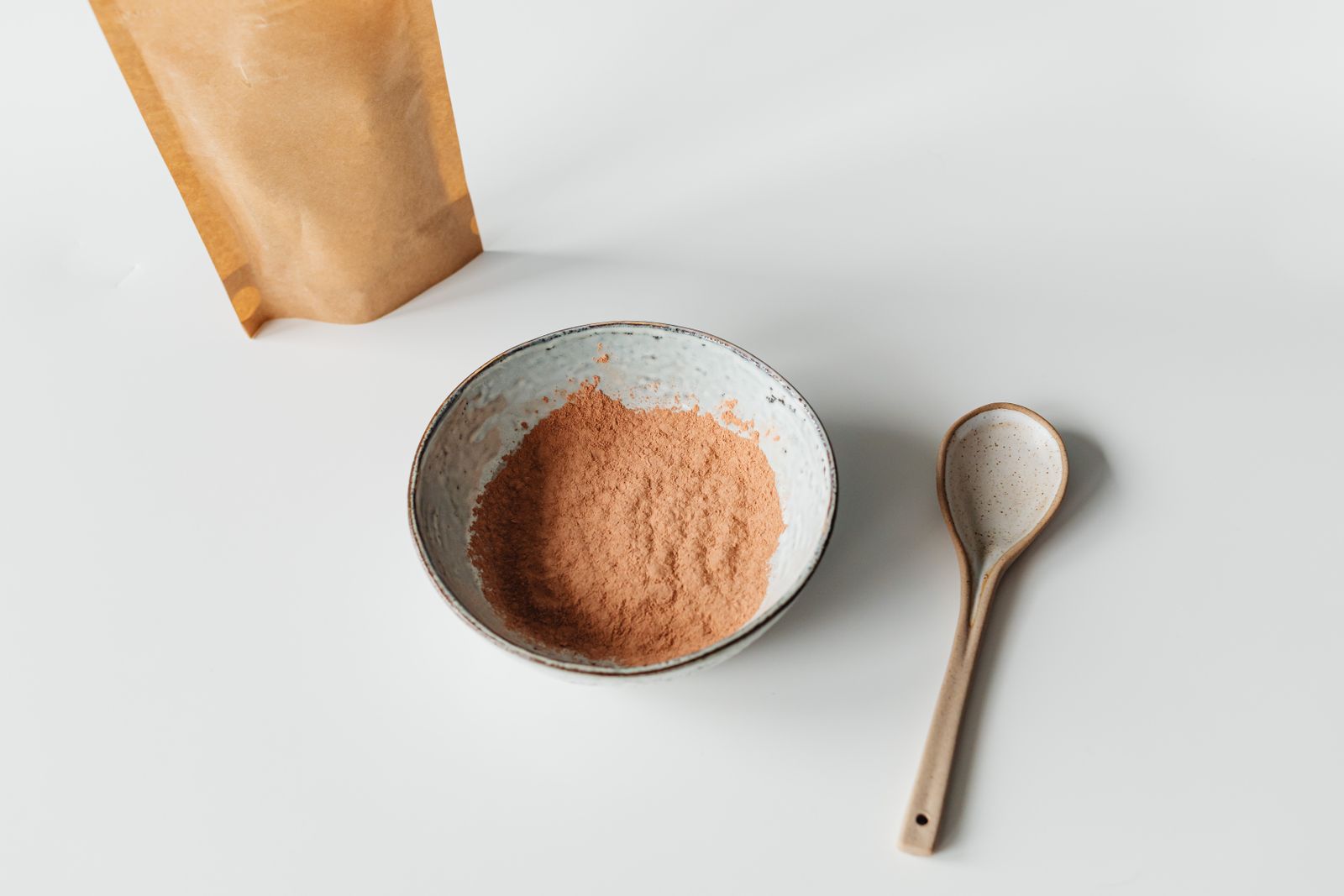 Poudre noire de charbon actif dans une coupelle en céramique sur table en bois clair, ambiance pharmacie naturelle, lumière douce