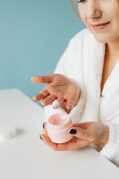 Close-up of a woman applying cream, emphasizing skincare routine and personal care.