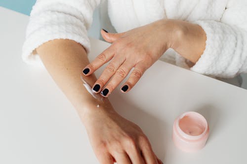 Free Close Up Photo of a Person Applying Cream on Her Arm Stock Photo