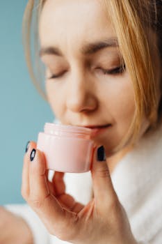 Close-up of woman with eyes closed enjoying fragrance from a creamy cosmetic jar.