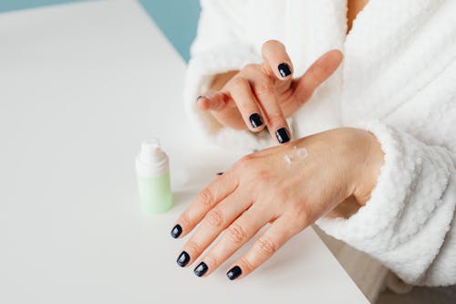 Free Close-up view of hands applying skincare cream, emphasizing skincare and beauty. Stock Photo