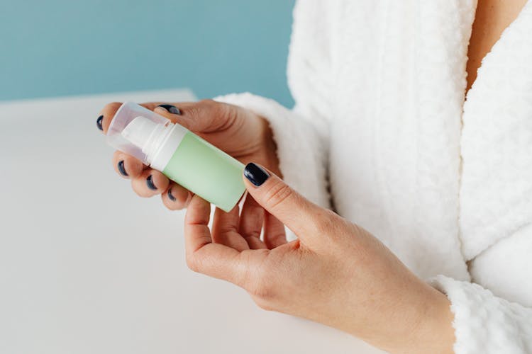 Woman Holding A Skincare Product Bottle In Her Hands