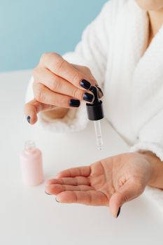 Close-up of woman's hands using a dropper for skincare routine.