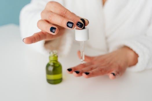 Close-up of a woman applying skincare serum with a dropper to her hand.
