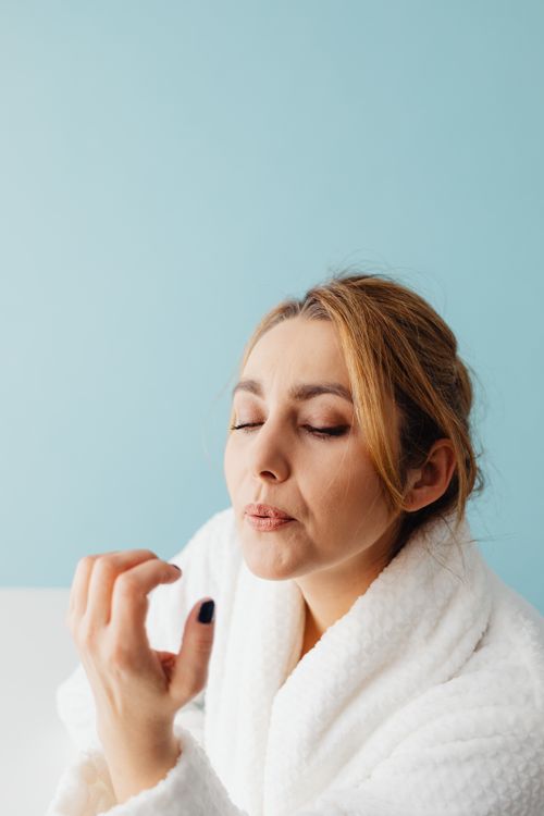 Free Woman in bathrobe enjoying a relaxing spa day with closed eyes and painted nails. Stock Photo