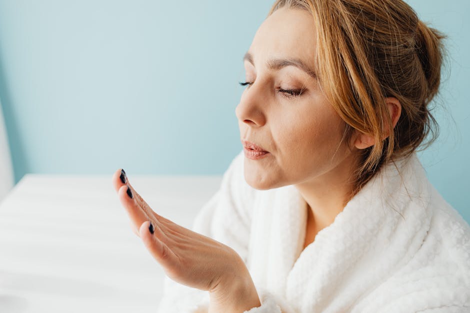 Muotoilutekniikat kotona: nopeasti ja näyttävästi Muotoilutekniikat kotona: nopeasti ja näyttävästi - Woman in a bathrobe blowing on her manicured nails for self-care.