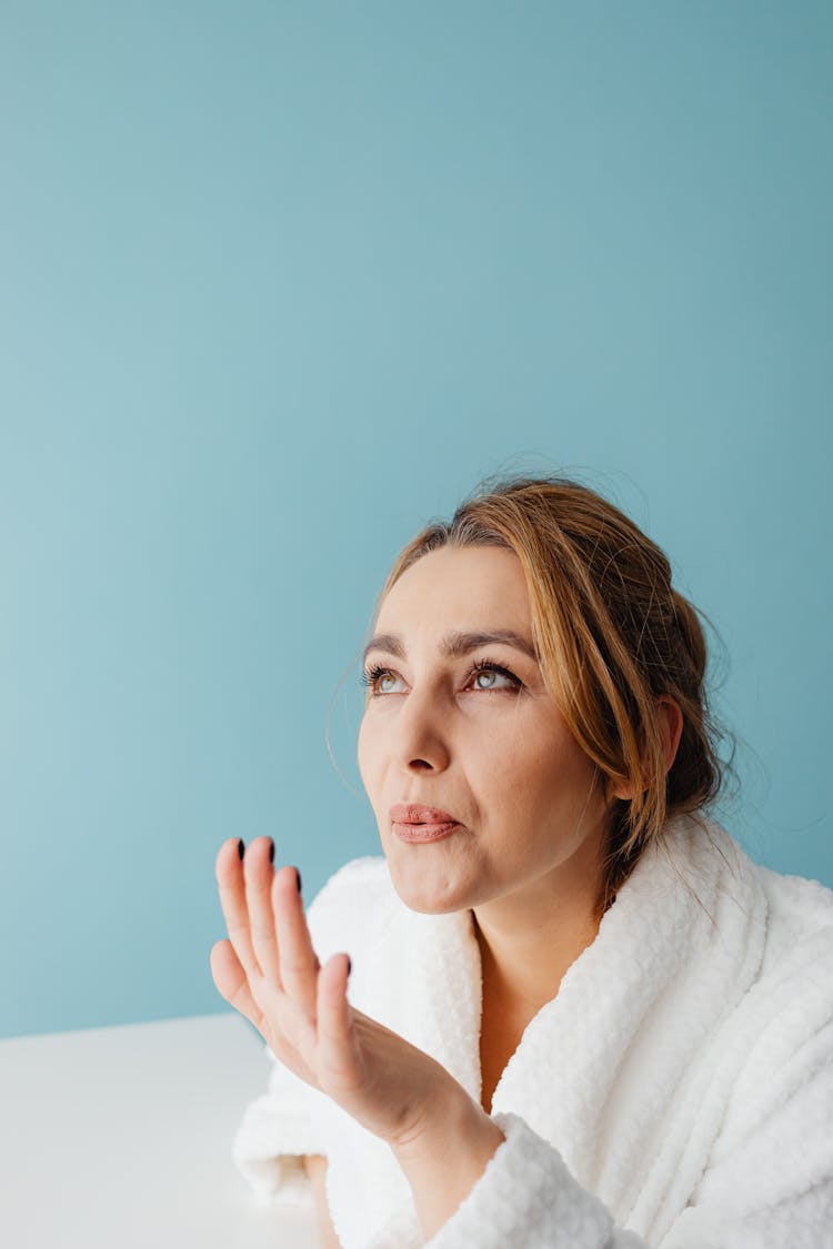 Woman In Bathrobe Blowing On Drying Nails