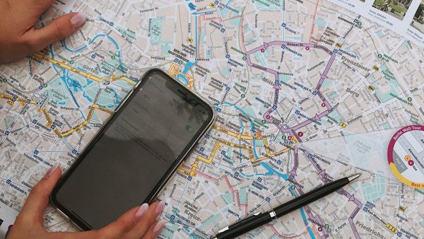 Hands interacting with a city map and smartphone, highlighting travel planning