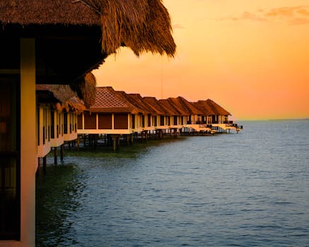 Idyllic view of overwater bungalows against a vibrant tropical sunset, perfect for vacation retreats.