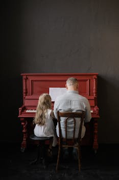 Elderly man and young girl bonding over music while playing piano indoors