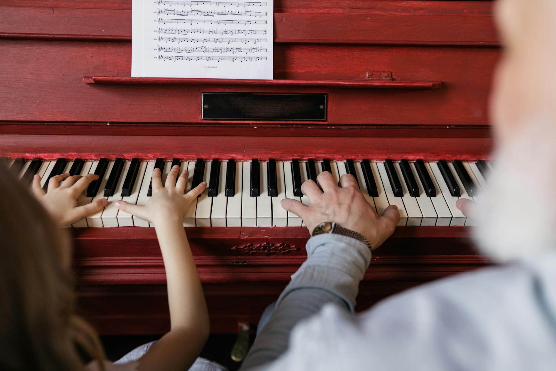 A tender moment of a grandparent teaching a child to play the piano.