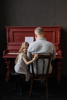 A senior man and young girl playing piano together, fostering musical bonding.